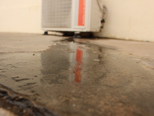 Wet floor caused by air conditioner leaking in the background.