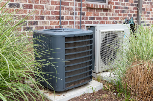 A central air conditioning unit installed next to a heat pump unit outside of a residential building.