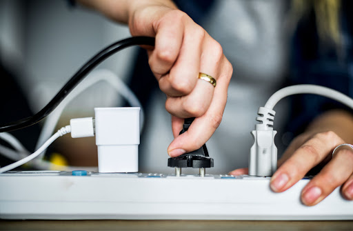 A person plugging a power cord into an extension cord.