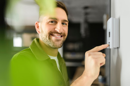 Man smiling at you while changing thermostat in his home in New Orleans.