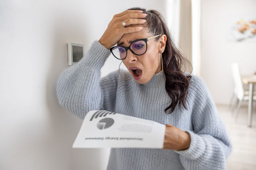 A woman with a shocked expression looking at a bill.