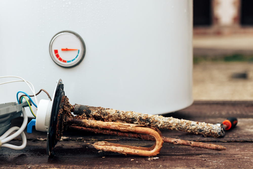 rusted anode rod laid out in front of old water heater