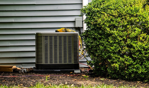 Outdoor AC unit near a bush.
