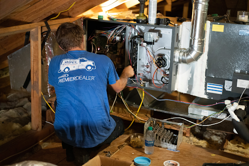 Keefe's HVAC technician performing heating maintenance on furnace.