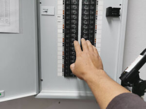 Homeowner checking electrical panel for tripped circuit breakers.