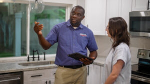 Keefe's electrician explaining to homeowner why lights flicker when she turns on appliances.